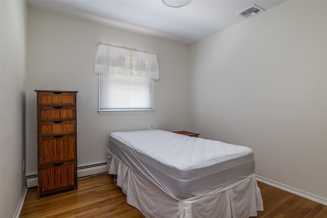 563 Long Beach Rd, Island Park, NY 11558 - bedroom featuring baseboard heating, wood finished floors, and baseboards