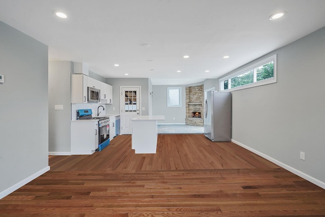 3061 Xavier Ct, Oceanside, NY 11572 - kitchen with stainless steel appliances, light countertops, a fireplace, white cabinets, and wood finished floors