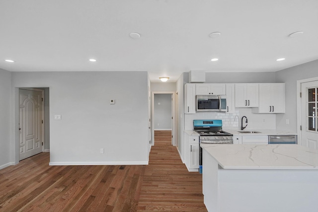 3061 Xavier Ct, Oceanside, NY 11572 - kitchen with stainless steel appliances, a sink, wood finished floors, white cabinets, and light stone counters