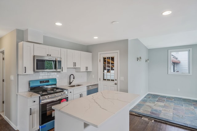 3061 Xavier Ct, Oceanside, NY 11572 - kitchen featuring stainless steel appliances, a sink, white cabinetry, a center island, and light stone counters