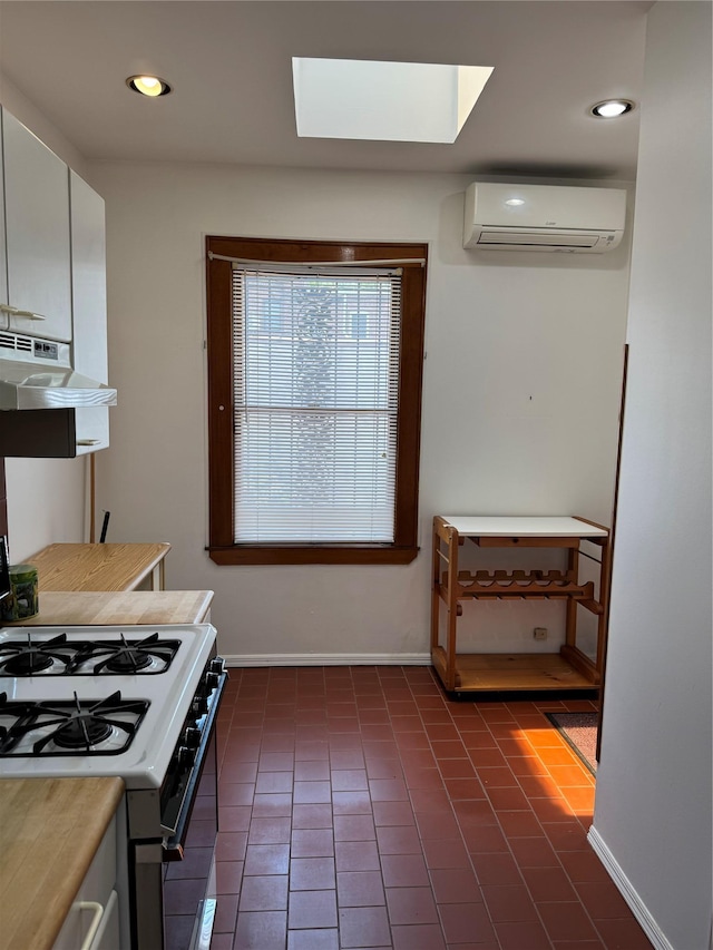 6472 84th St, Middle Village, NY 11379 - kitchen featuring a wall mounted air conditioner, under cabinet range hood, white gas range oven, dark tile patterned flooring, and recessed lighting