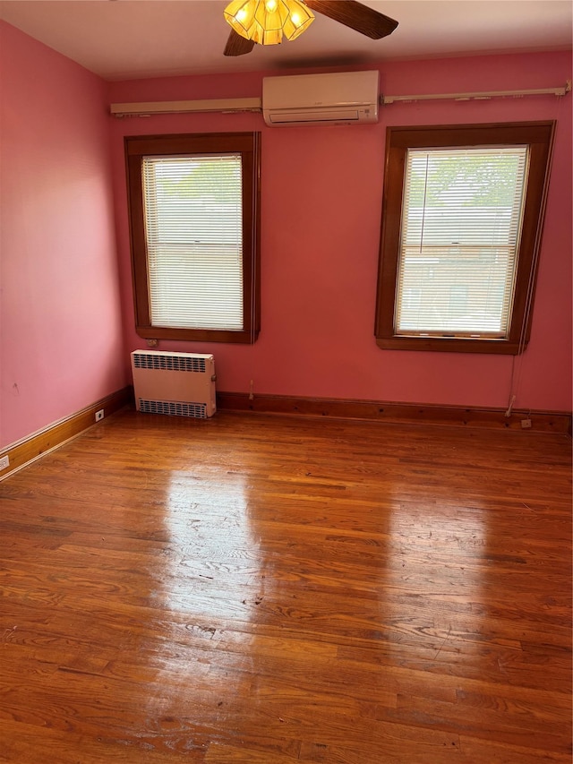 6472 84th St, Middle Village, NY 11379 - unfurnished room with an AC wall unit, radiator, wood finished floors, and ceiling fan
