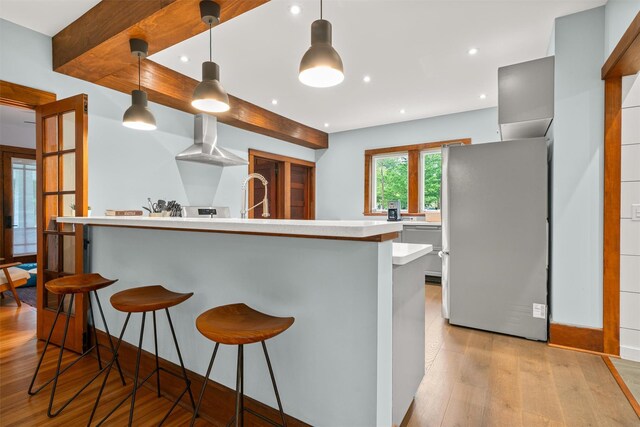 858 N Branch Hortonville Rd, North Branch, NY 12745 - kitchen with freestanding refrigerator, wall chimney range hood, light countertops, light wood-style floors, and a breakfast bar area