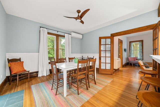858 N Branch Hortonville Rd, North Branch, NY 12745 - dining area with an AC wall unit, wainscoting, light wood-style flooring, french doors, and ceiling fan