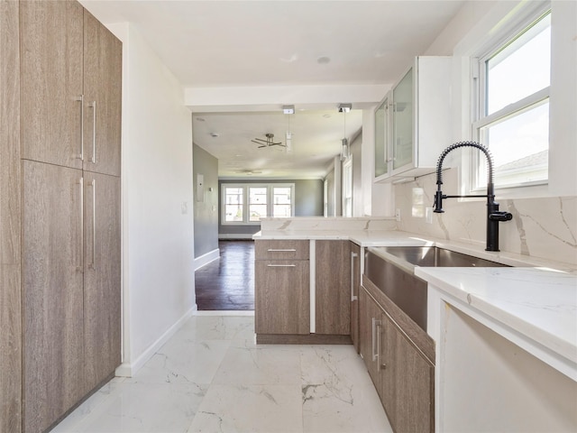 34 Woodland Ave, Poughkeepsie, NY 12603 - kitchen with light stone countertops, a sink, a peninsula, light marble finish flooring, and glass insert cabinets