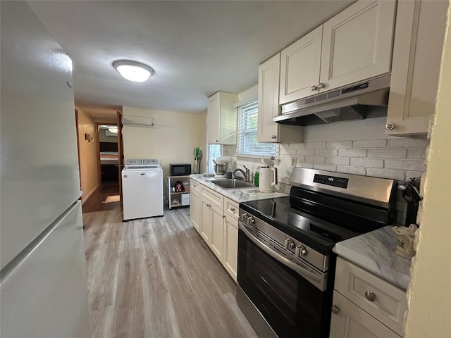 50 Tangier Dr, Sound Beach, NY 11789 - kitchen with electric range, washer / dryer, under cabinet range hood, light wood-type flooring, and a sink