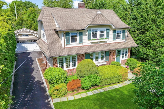 489 Manor Ln, Pelham, NY 10803 - view of front facade with roof with shingles, brick siding, a chimney, and an outdoor structure