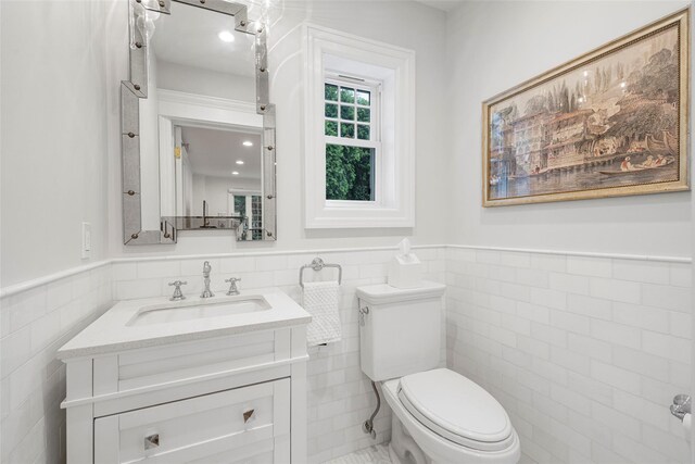 489 Manor Ln, Pelham, NY 10803 - half bathroom with tile walls, toilet, a wainscoted wall, and vanity