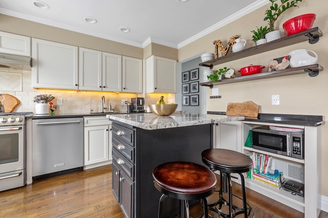 1696 Coral Rd, East Meadow, NY 11554 - kitchen featuring appliances with stainless steel finishes, white cabinetry, light stone countertops, a breakfast bar area, and crown molding