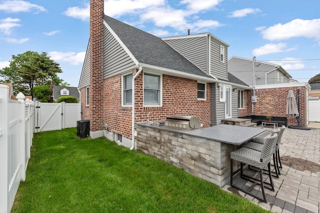1696 Coral Rd, East Meadow, NY 11554 - back of property featuring a gate, an outdoor kitchen, brick siding, a shingled roof, and a patio