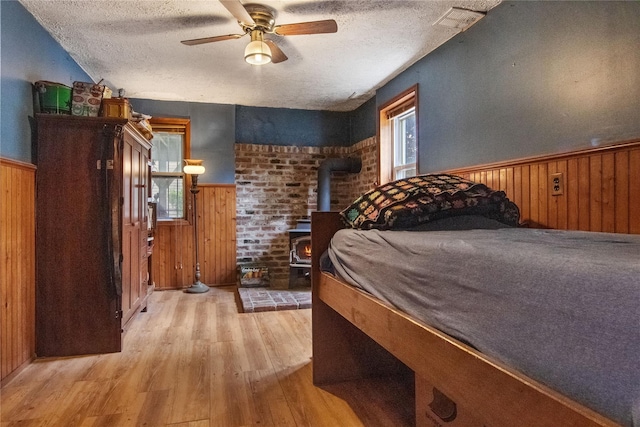 230 Pennyfield Ave, Bronx, NY 10465 - bedroom featuring wood finished floors, a wainscoted wall, a textured ceiling, wooden walls, and a wood stove