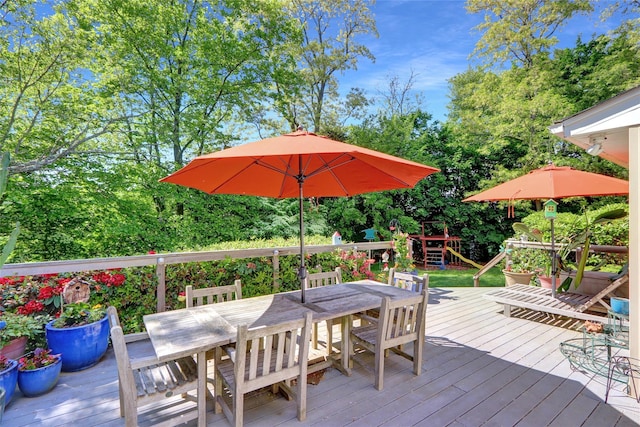 12 Bridle Path Ln, Port Jefferson, NY 11777 - wooden terrace featuring outdoor dining area, a playground, and view of wooded area