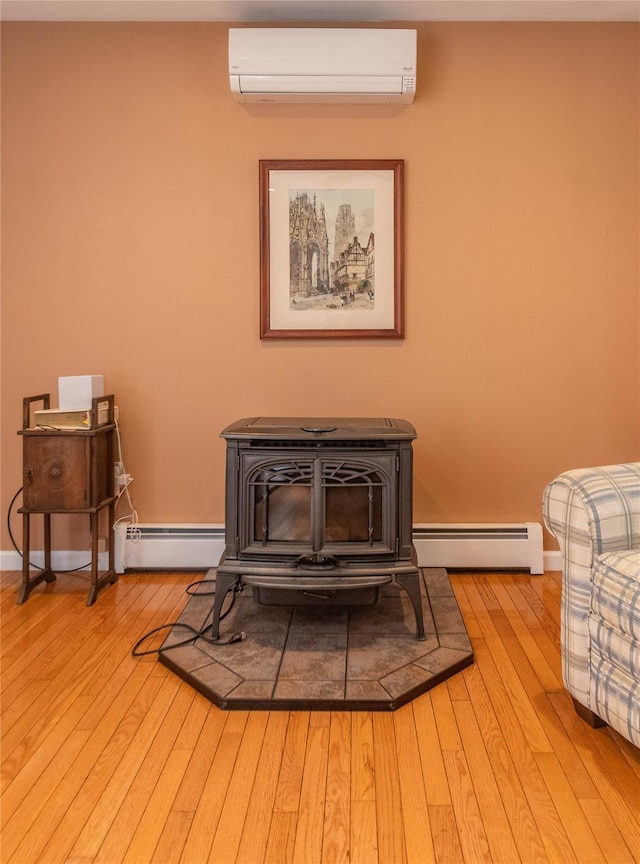 57 Decker Dr, Washingtonville, NY 10992 - detailed view of a wall mounted AC, a baseboard heating unit, a wood stove, and wood finished floors