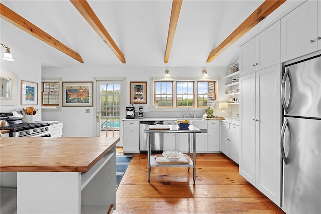 140AND144 Damascus Rd, East Quogue, NY 11942 - kitchen featuring stainless steel appliances, butcher block countertops, open shelves, beam ceiling, and white cabinets