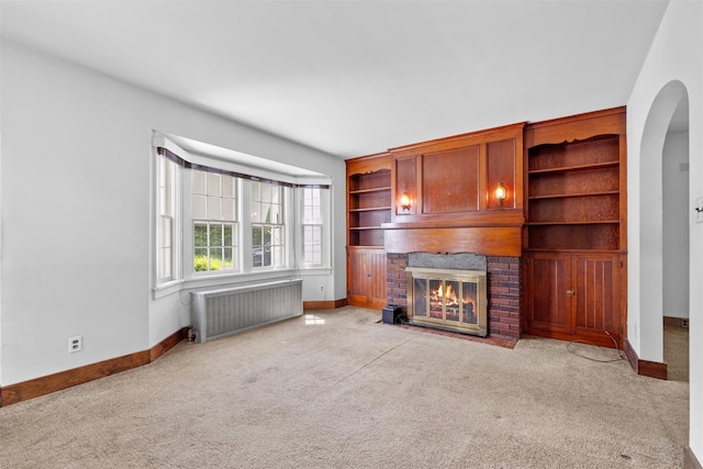 61 Spackenkill Rd, Poughkeepsie, NY 12603 - unfurnished living room featuring radiator heating unit, baseboards, carpet floors, a brick fireplace, and arched walkways