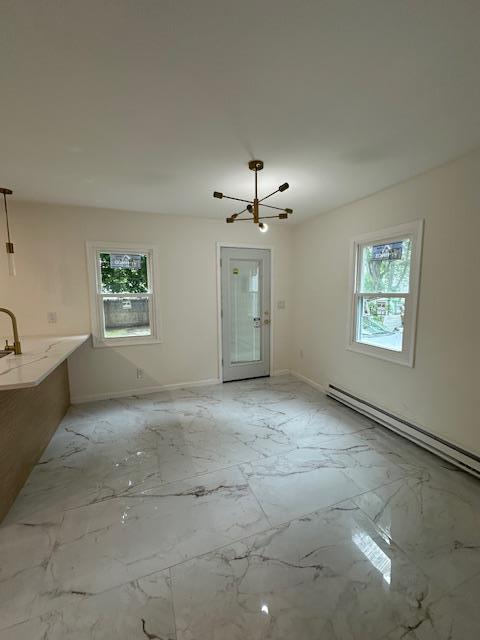 140 Ball St, Port Jervis, NY 12771 - unfurnished living room with healthy amount of natural light, a chandelier, light marble finish flooring, and a baseboard heating unit