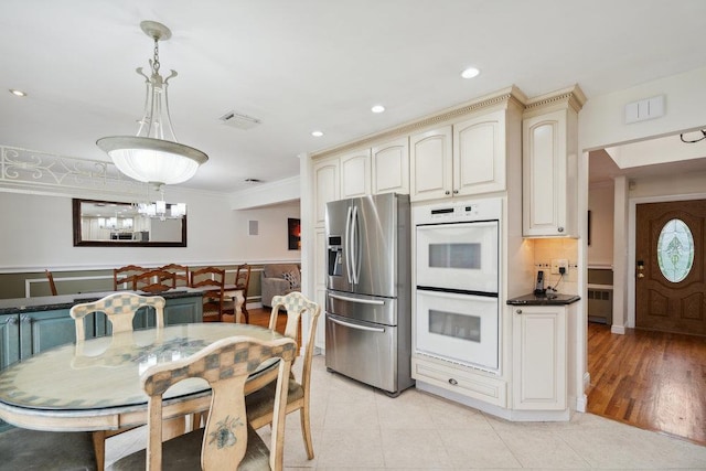 5 Coventry Rd, Syosset, NY 11791 - kitchen featuring stainless steel fridge, white double oven, cream cabinets, crown molding, and pendant lighting