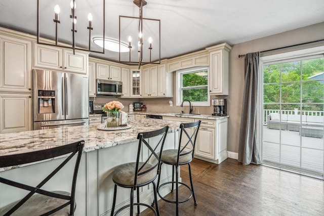 12 Pleasant Pl, Farmingville, NY 11738 - kitchen featuring appliances with stainless steel finishes, cream cabinets, a breakfast bar area, light stone counters, and decorative light fixtures