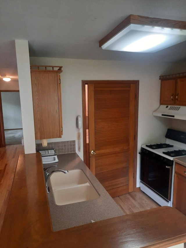 1502 Evergreen Ct, Highland Mills, NY 10930 - kitchen featuring gas range, range hood, light wood-style floors, a sink, and brown cabinets