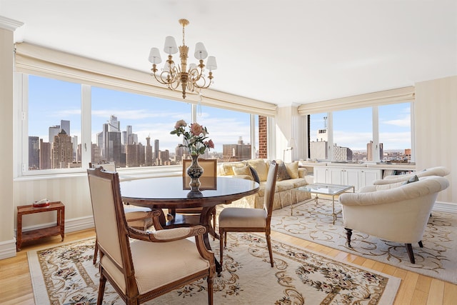 322 W 57th St Unit 33U, New York Manhattan, NY 10019 - dining space featuring a skyline view, a chandelier, light wood finished floors, and baseboards
