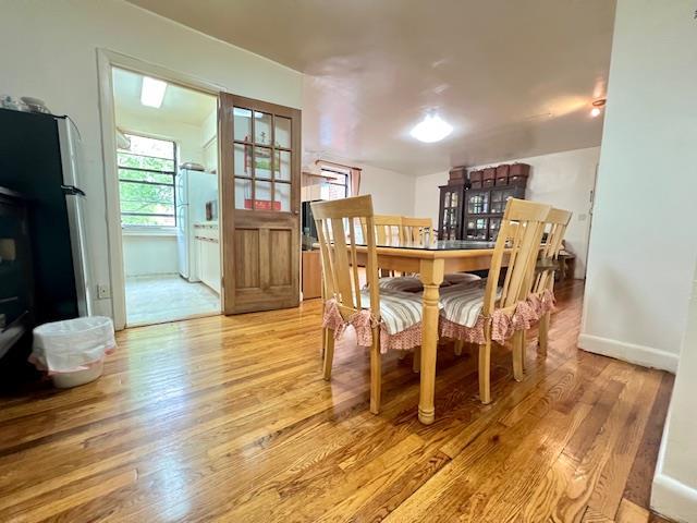 215-19 48th Ave Unit 3C, Bayside, NY 11364 - dining space with light wood-style flooring, a wood stove, and baseboards