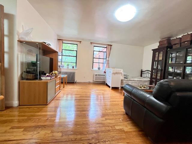 215-19 48th Ave Unit 3C, Bayside, NY 11364 - living room featuring radiator heating unit, wood finished floors, and a wall unit AC