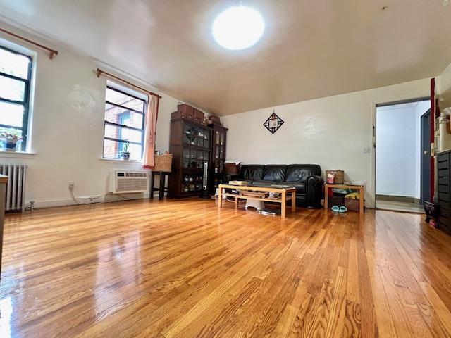 215-19 48th Ave Unit 3C, Bayside, NY 11364 - living area featuring radiator heating unit, wood finished floors, and a wall mounted AC