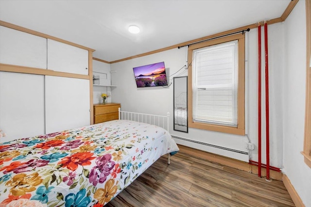735 E 216th St, Bronx, NY 10467 - bedroom featuring a baseboard heating unit, wood finished floors, a closet, crown molding, and baseboards