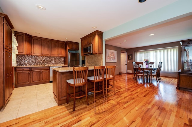 1158 Lorraine Dr, Franklin Square, NY 11010 - kitchen featuring stainless steel microwave, freestanding refrigerator, backsplash, a kitchen bar, and light stone counters