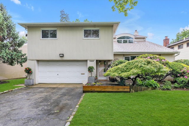 1055 Cedarhurst St, North Woodmere, NY 11581 - tri-level home featuring asphalt driveway, a garage, a front lawn, a chimney, and roof with shingles
