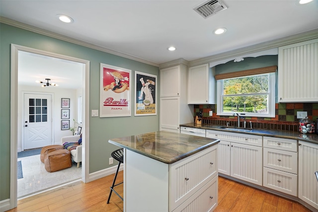 801 Syska Rd, Ossining, NY 10562 - kitchen featuring a sink, backsplash, crown molding, a kitchen breakfast bar, and light wood-style flooring