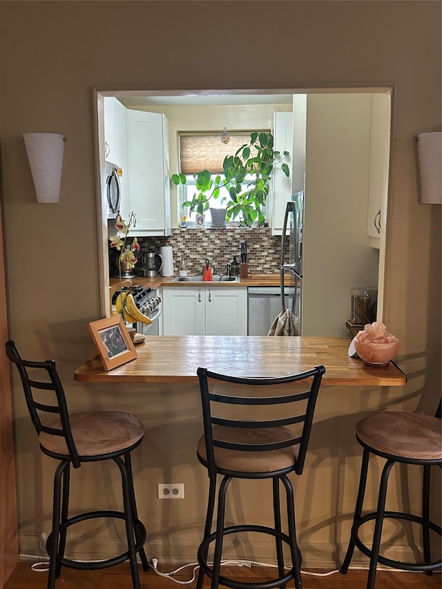 110-20 71st Ave Unit 411, Forest Hills, NY 11375 - kitchen with butcher block countertops, stainless steel appliances, white cabinetry, and backsplash