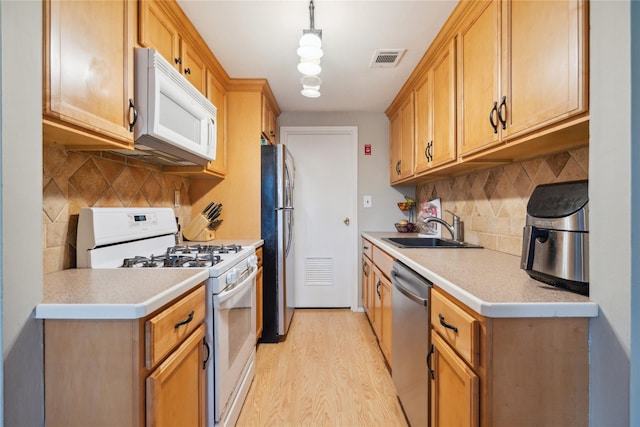 65 Sagamore Hills Dr, Port Jefferson Station, NY 11776 - kitchen with appliances with stainless steel finishes, a sink, light wood finished floors, light countertops, and decorative backsplash