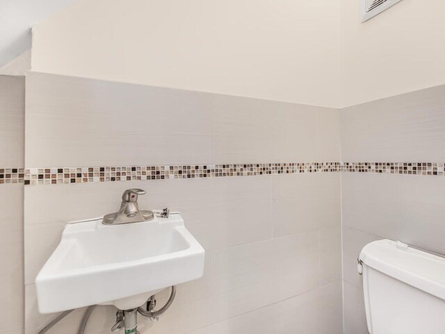 3333 Tiemann Ave, Bronx, NY 10469 - half bath featuring tile walls, a sink, and toilet