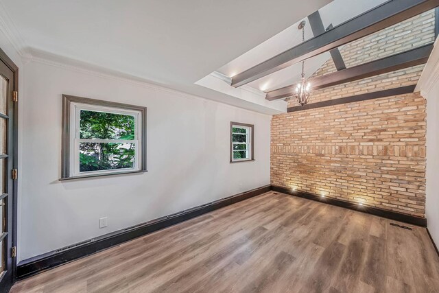 1 William St, Glen Cove, NY 11542 - spare room featuring brick wall, wood finished floors, healthy amount of natural light, a chandelier, and ornamental molding