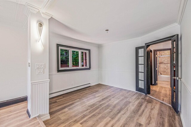 1 William St, Glen Cove, NY 11542 - unfurnished room with baseboard heating, wood finished floors, a wainscoted wall, and crown molding