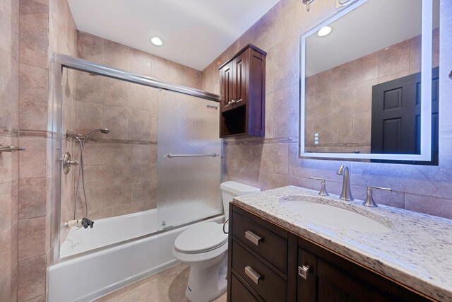 1 William St, Glen Cove, NY 11542 - full bathroom with tile walls, toilet, vanity, combined bath / shower with glass door, and tile patterned flooring