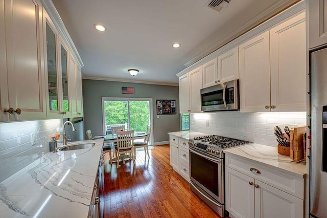 86 Manitou Trl, Kings Park, NY 11754 - kitchen featuring appliances with stainless steel finishes, a sink, white cabinetry, ornamental molding, and light stone counters