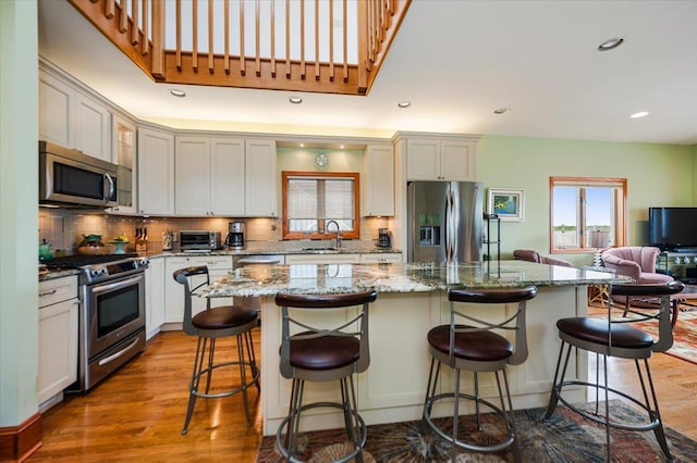 991 W Park Ave, Long Beach, NY 11561 - kitchen featuring appliances with stainless steel finishes, a sink, wood finished floors, tasteful backsplash, and recessed lighting