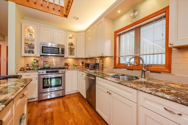 991 W Park Ave, Long Beach, NY 11561 - kitchen with stainless steel appliances, a sink, backsplash, light wood-style floors, and light stone counters