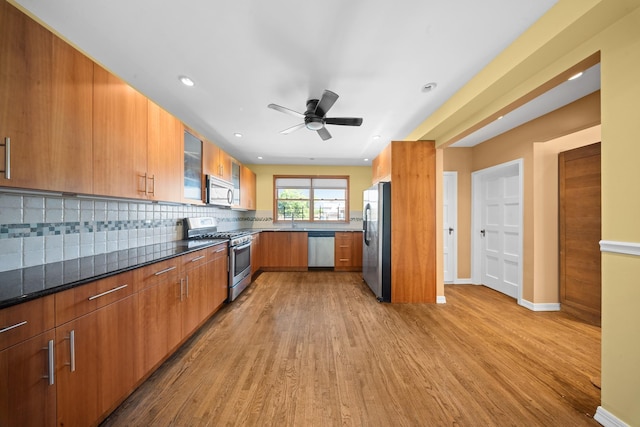 40-40 203rd St Unit 12B, Bayside, NY 11361 - kitchen with appliances with stainless steel finishes, light wood-style floors, decorative backsplash, ceiling fan, and brown cabinets