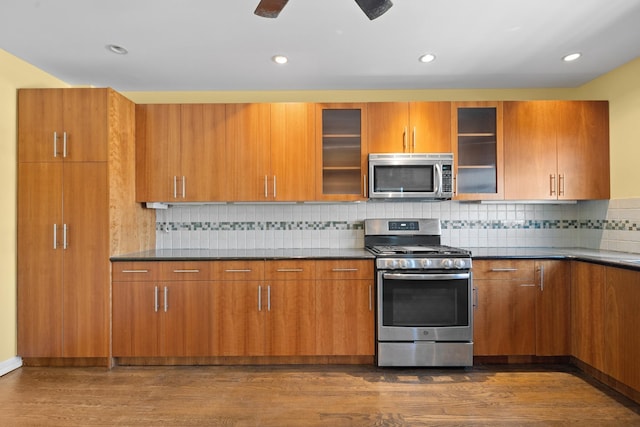 40-40 203rd St Unit 12B, Bayside, NY 11361 - kitchen with appliances with stainless steel finishes, dark wood-style flooring, brown cabinetry, dark countertops, and recessed lighting
