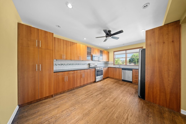 40-40 203rd St Unit 12B, Bayside, NY 11361 - kitchen with stainless steel appliances, wood finished floors, brown cabinetry, backsplash, and ceiling fan