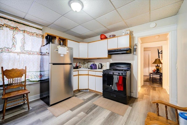 5 Gray Sts, Poughkeepsie, NY 12601 - kitchen with freestanding refrigerator, black gas stove, under cabinet range hood, a drop ceiling, and light wood-style floors