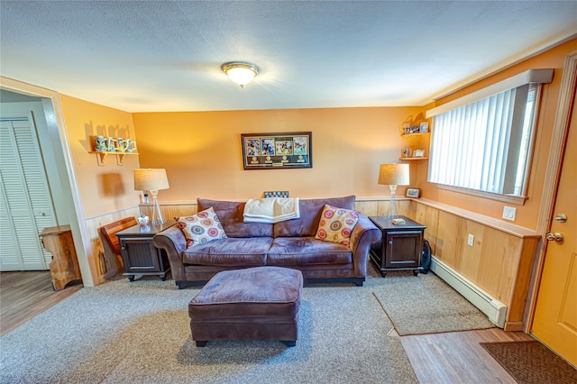 964 Manor Ln, Bay Shore, NY 11706 - living area with a baseboard heating unit, a wainscoted wall, wood finished floors, wooden walls, and carpet flooring