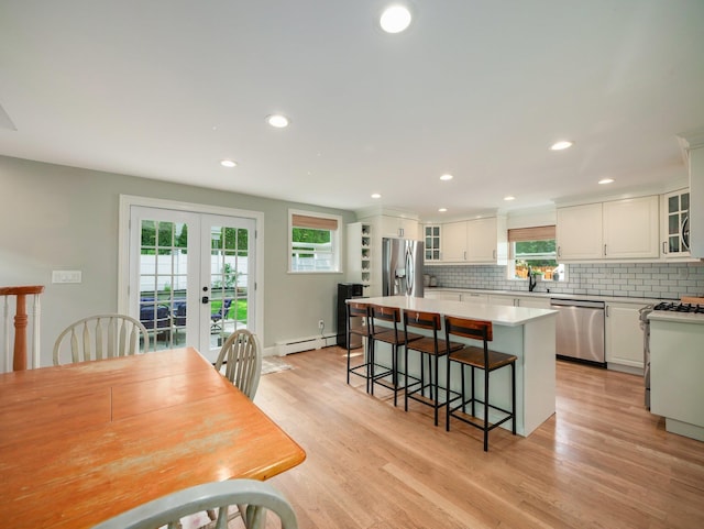29 Chestnut St, Pearl River, NY 10965 - kitchen with appliances with stainless steel finishes, a baseboard heating unit, a breakfast bar area, french doors, and white cabinets