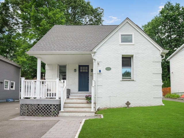29 Chestnut St, Pearl River, NY 10965 - view of front of house featuring a front yard, roof with shingles, brick siding, and covered porch