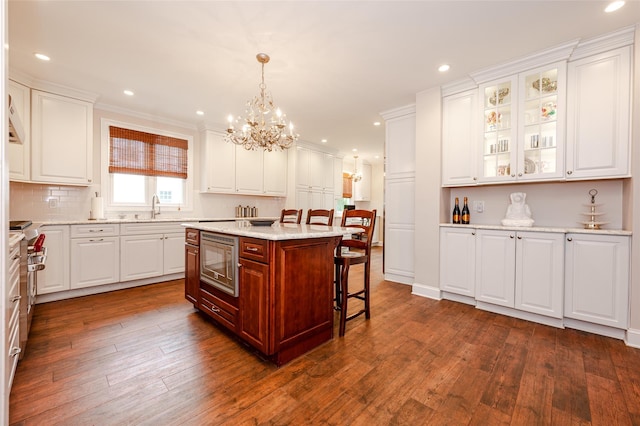 70 Loines Ave, Merrick, NY 11566 - kitchen featuring appliances with stainless steel finishes, white cabinetry, a chandelier, a sink, and a kitchen breakfast bar