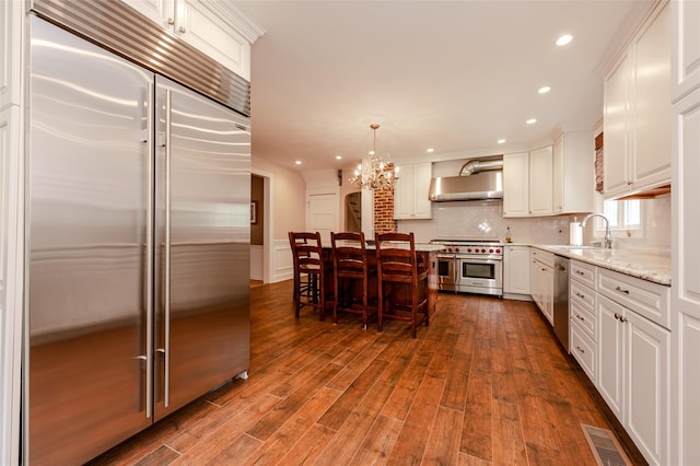 70 Loines Ave, Merrick, NY 11566 - kitchen with premium appliances, a chandelier, a sink, white cabinets, and recessed lighting