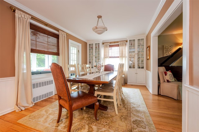 70 Loines Ave, Merrick, NY 11566 - dining area with radiator heating unit, light wood-style flooring, a wainscoted wall, crown molding, and a decorative wall